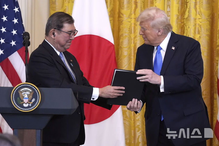 [워싱턴=AP/뉴시스]도널드 트럼프 미국 대통령이 7일(현지 시간) 백악관에서 이시바 총리와 회담한 후 공동기자회견에서 함께 찍은 사진을 선물하고 있다. 2025.02.08.