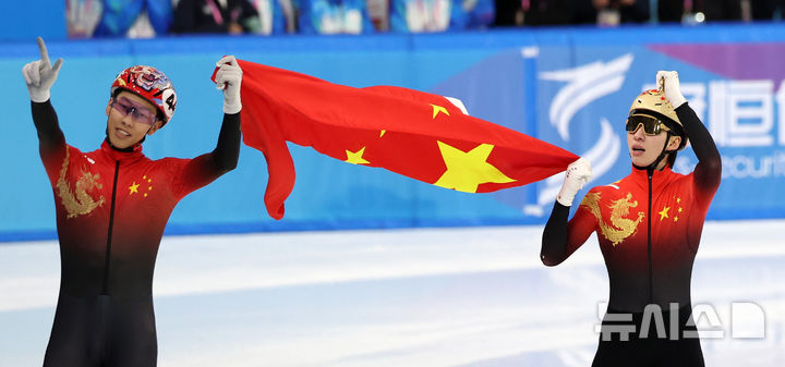 [하얼빈(중국)=뉴시스] 김선웅 기자 = 지난 8일(현지 시간) 중국 하얼빈 헤이룽장 빙상훈련센터에서 열린 2025 하얼빈 동계 아시안게임 쇼트트랙 남자 500m 결승 경기에서 중국 린 샤오쥔(오른쪽)이 금메달을 확정지은 뒤 4위 쑨룽과 함께 오성홍기를 들고 기뻐하고 있다. 2025.02.08. mangusta@newsis.com