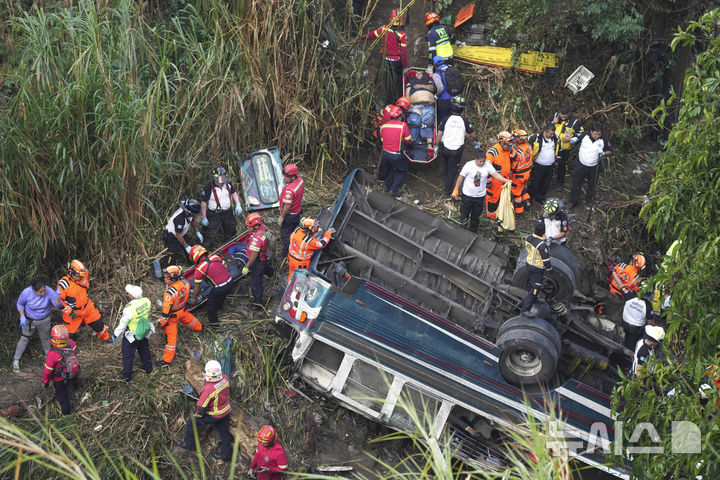 [AP/뉴시스] 10일 과테말라 수도 외곽에서 소방관들이 계곡으로 추락한 버스 사고현장에서 일하고 있다. 55명이 사망했다.