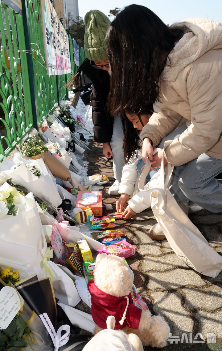 [대전=뉴시스] 강종민 기자 = 11일 오후 초등학생 피살사건이 발생한 대전 서구 관저동의 한 초등학교 정문 옆 담장에서 초등생들이 국화꽃과 과자·음료 등을 놓으며 고 김하늘(8) 양을 추모하고 있다. 2025.02.11. ppkjm@newsis.com