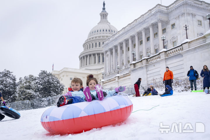 [워싱턴=AP/뉴시스] 12일(현지 시간) 미국 워싱턴 DC에 폭설이 내린 후 의사당 인근 언덕에서 어린이들이 눈썰매를 즐기고 있다. 켄터키 주를 비롯한 미국 전지역이 15일부터 겨울 폭우와 폭설, 돌발 홍수와 산사태등 기후 재난에 시달리고 있다. 2025.02.17.
