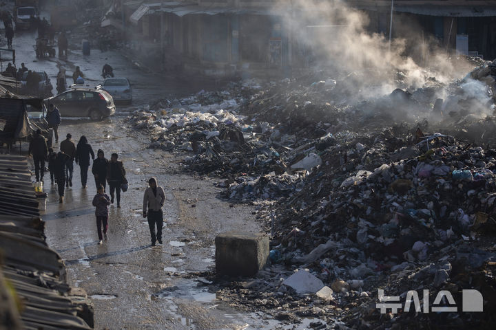 [가자시티=AP/뉴시스] 지난 12일(현지 시간) 가자지구 가자시티에서 팔레스타인 주민들이 불에 타는 쓰레기 더미 옆을 지나고 있다. 이집트는 세계은행과 함께 도널드 트럼프 대통령의 가자 구상을 대체할 전후 계획을 수립 중인 것으로 알려졌다. 2025.02.17.