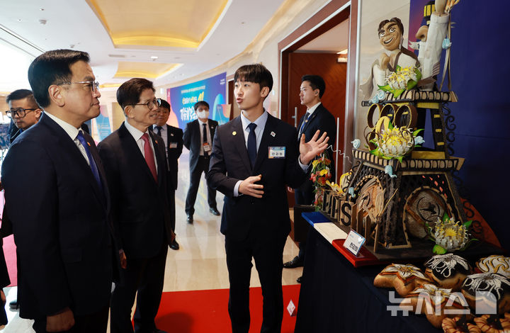 [서울=뉴시스] 조수정 기자 = 최상목 대통령 권한대행 부총리 겸 기획재정부 장관이 13일 서울 송파구 잠실 롯데호텔 월드에서 열린 '국제기능올림픽 선수단 격려 오찬'에 참석하기 앞서 제빵 부문 은메달 한강희 선수의 작품 설명을 듣고 있다. (대통령실통신사진기자단) 2025.02.13. chocrystal@newsis.com