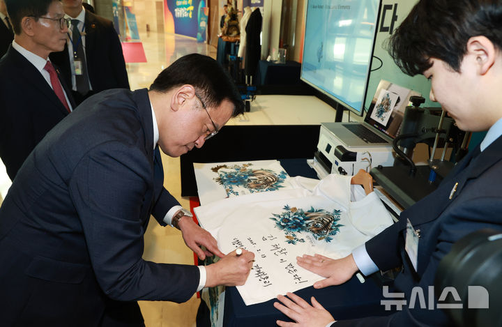 [서울=뉴시스] 조수정 기자 = 최상목 대통령 권한대행 부총리 겸 기획재정부 장관이 13일 서울 송파구 잠실 롯데호텔 월드에서 열린 '국제기능올림픽 선수단 격려 오찬'에 참석하기 앞서 그래픽 티셔츠에 그래픽 디자인 금메달 김채환 씨 격려 문구와 서명을 남기고 있다. (대통령실통신사진기자단) 2025.02.13. chocrystal@newsis.com