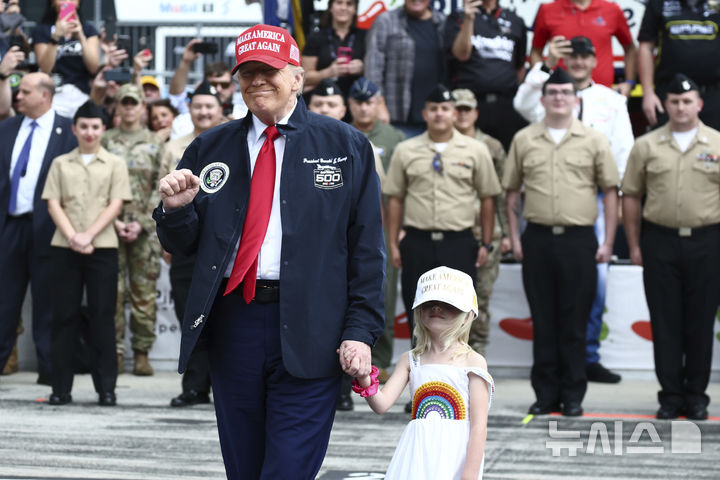 [데이토나비치=AP/뉴시스] 도널드 트럼프 미국 대통령이 손녀 캐롤리나의 손을 잡고 16일(현지 시간) 플로리다주 데이토나 비치의 데이토나 인터내셔널 스피드웨이에서 열리는 자동차 경주 대회 '데이토나 500' 경주장에 들어서고 있다. 2025.02.17.
