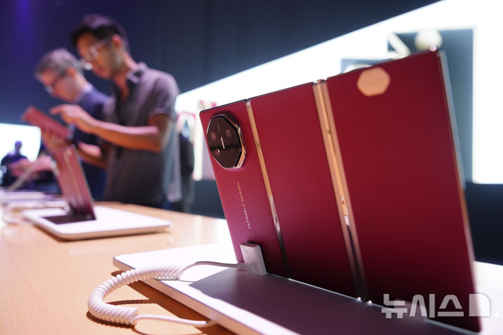 [쿠알라룸프=AP/뉴시스] 중국 최대 통신장비 제조업체 화웨이가 세계 최초 두 번 접히는 트리플 폴더블(3단폰)을 해외 시장에서 판매하기 시작했다. 18일(현지 시간) 말레이시아 쿠알라룸프에서 열린 화웨이 신제품 공개행사에서 사람들이 화웨이 트리플 폴더블폰 ‘메이트XT’을 살펴보는 모습. 2025.02.19