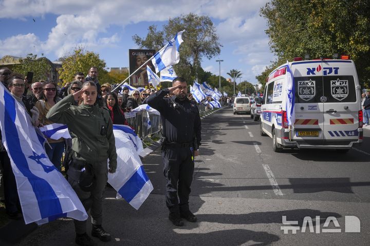 [텔아비브=AP/뉴시스] 20일(현지 시간) 이스라엘 텔아비브 인질 광장에서 이스라엘인들이 하마스에 억류됐다가 숨진 이스라엘 인질 4명의 시신이 송환되자 경찰들이 경례하고 있다. 하마스는 앞서 이스라엘 인질 시리 비바스와 두 아들 아리엘·크피르 비바스 그리고 오데드 리프시츠 등 4명의 시신을 돌려보냈다. 2025.02.21.
