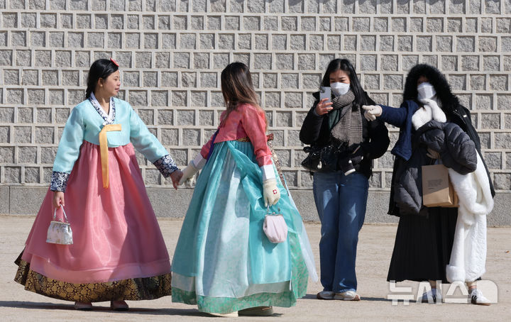 [서울=뉴시스] 김명원 기자 = 전국이 맑은 가운데 아침 최저기온이 영하 12도까지 떨어지는 강추위가 이어지는 가운데 23일 서울 종로구 경복궁에서 관광객들이 방한복을 벗고 추위를 이겨내며 밝은 모습으로 기념촬영을 하고 있다. 2025.02.23. kmx1105@newsis.com