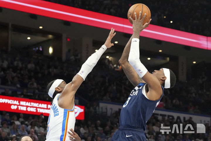 Minnesota Timberwolves forward Jaden McDaniels, right, looks to shoot over Oklahoma City Thunder guard Shai Gilgeous-Alexander, left, during the second half of an NBA basketball game, Monday, Feb. 24, 2025, in Oklahoma City. (AP Photo/Kyle Phillips)