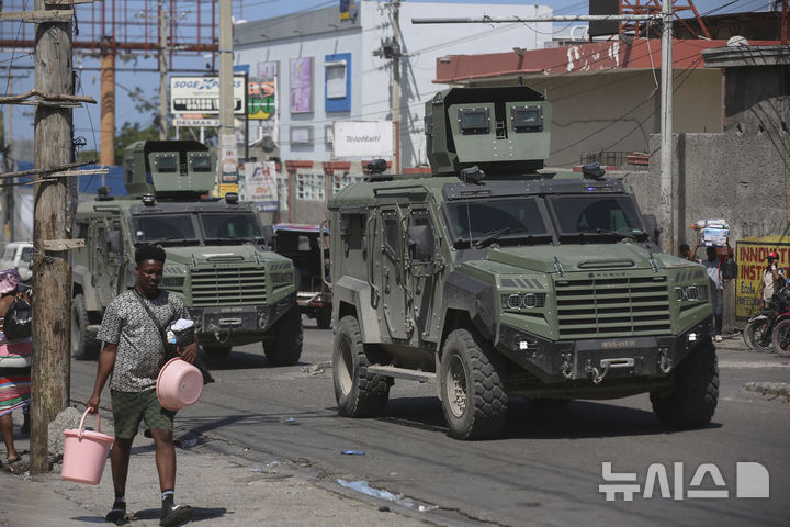 [포르토프랭스=AP/뉴시스] 25일(현지 시간) 아이티 포르토프랭스 델마 지역에서 주민들이 무장 갱단 폭력을 피해 집을 떠나는 가운데 케냐 경찰 차량이 거리를 순찰하고 있다. 케냐가 주도하는 다국적 경찰이 아이티 군·경과 함께 치안 유지 임무를 수행 중이지만, 인력과 장비 부족으로 어려움을 겪고 있다. 2025.02.26.