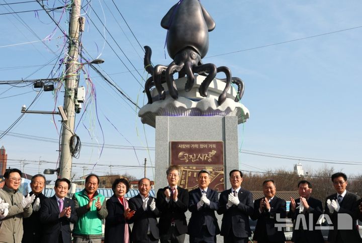 [포항=뉴시스] 송종욱 기자 = 포항시가 드라마 '갯마을 차차차'로 국내외 여행객의 관광 명소로 거듭난 북구 청하면에 국내외 관광객을 위한 편의 시설을 확충했다. 사진은 27일 제막한 청하공진시장에 오징어 조형물을 제막한 후 참석자들이 기념 촬영을 하는 모습. (사진=포항시 제공) 2025.02.27. photo@newsis.com 
