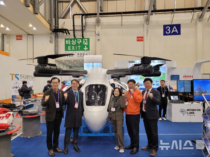 [부산=뉴시스]27일 부산 벡스코 제1전시관에서 열리고 있는 '2025 드론쇼코리아(DSK 2025)' 경남 홍보관을 찾은 김명주(왼쪽서 두 번째) 경남도 경제부지사가 경남형 미래항공기체 컨소시엄이 개발 중인 AAV(Advanced Air Vehicle) 시제기 실물모형 앞에서 기념촬영하고 있다.(사진=경남도 제공) 2025.02.27. photo@newsis.com