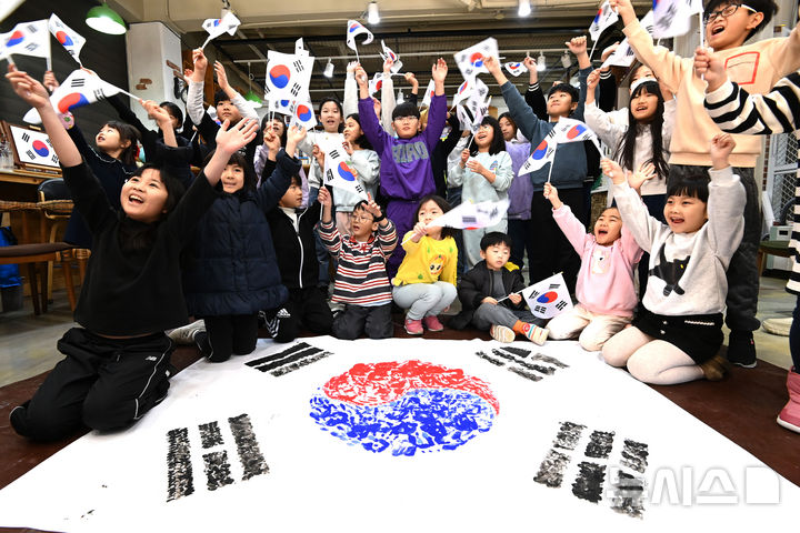 [수원=뉴시스] 김종택 기자 = 제106주년 삼일절을 이틀 앞둔 27일 경기도 수원시 세류1동 새마을문고 책먹는 아이들에서 열린 '나라사랑 한마음 손도장 태극기 만들기' 행사에서 어린이들이 물감으로 직접 그린 손도장 태극기를 들어보이며 만세삼창을 외치고 있다. 2025.02.27. jtk@newsis.com