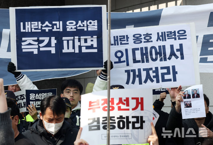 [서울=뉴시스] 김명년 기자 = 28일 오후 서울 동대문구 한국외국어대학교 정문에서 열린 윤석열 대통령 탄핵 반대 시국선언 뒤로 탄핵 촉구 측 손팻말이 보이고 있다. 2025.02.28. kmn@newsis.com