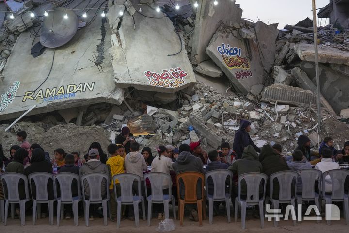 [라파=AP/뉴시스] 라마단 첫날인 3월 1일에 가자지구 남부 라파에서 팔레스타인 주민들이 파괴된 집과 건물 잔해에 둘러싸인 커다란 식탁에 모여 앉아 이프타르(금식 종료 후 식사)를 함께하고 있다. 2025.03.06.