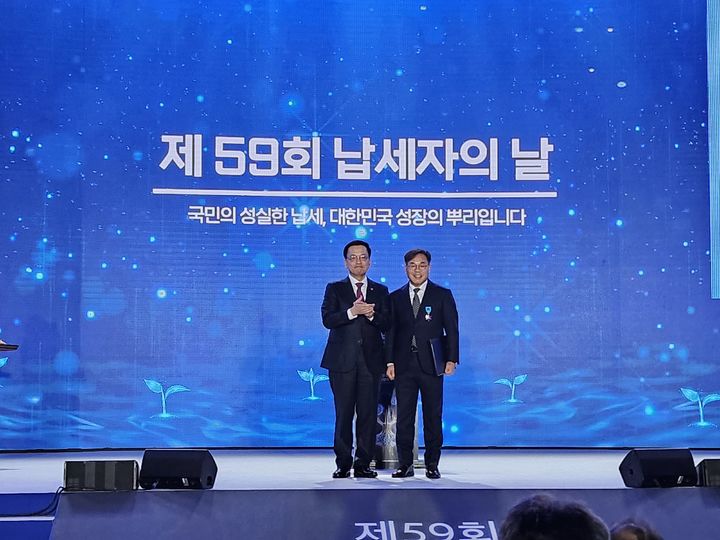 [창녕=뉴시스] 김태명(오른쪽) 리베라관광개발 회장이 최상목 대통령 권한대행 부총리 겸 기획재정부 장관으로부터 포장증을 받고 기념촬영을 하고 있다. (사진= 리베라관광개발 제공) 2025.03.05. photo@newsis.com *재판매 및 DB 금지