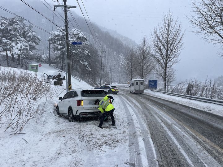 [강릉=뉴시스] 강릉경찰서가 4일 강릉시 왕산면 도마교 인근 도로에서 폭설로 인해 도로를 이탈한 차량에 고립된 운전자와 동승자 4명을 구조하고 있는 모습.(사진=강릉경찰서 제공) photo@newsis.com *재판매 및 DB 금지
