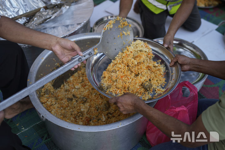 [두바이=AP/뉴시스] 6일(현지 시간) 아랍에미리트(UAE) 두바이에서 자원봉사자들이 라마단 단식을 마친 무슬림들에게 나눠줄 음식을 배식하고 있다. 2025.03.07.