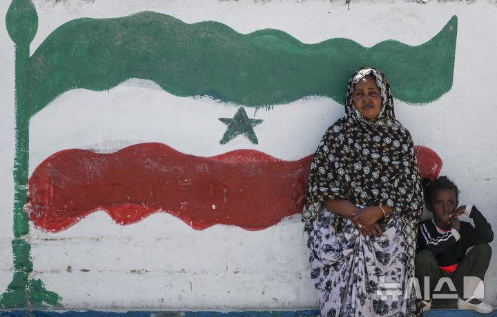 [하르게이사=AP/뉴시스] 2022년 2월 9일(현지 시간) 소말릴란드 수도 하르게이사에서 한 여성과 아이가 소말릴란드 국기가 그려진 벽화 앞에 서 있는 모습. 이스라엘은 26일 소말리아로부터 분리한 소말릴란드 공화국을 독립 국가로 인정했다. 2025.12.27.