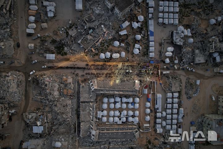 [가자시티=AP/뉴시스] 군사적 긴장감이 감도는 가운데에서도 이스라엘과 팔레스타인 무장 정파 하마스가 9일(현지 시간) 2단계 휴전 협상을 위한 준비를 계속하고 있다. 사진은 지난 6일 가자지구 가자시티에서 팔레스타인 주민들이 파괴된 집과 건물 잔해, 난민 텐트로 둘러싸인 대형 식탁에 모여 라마단 금식 종료 후 이프타르를 함께하고 있는 모습. 2025.03.09.