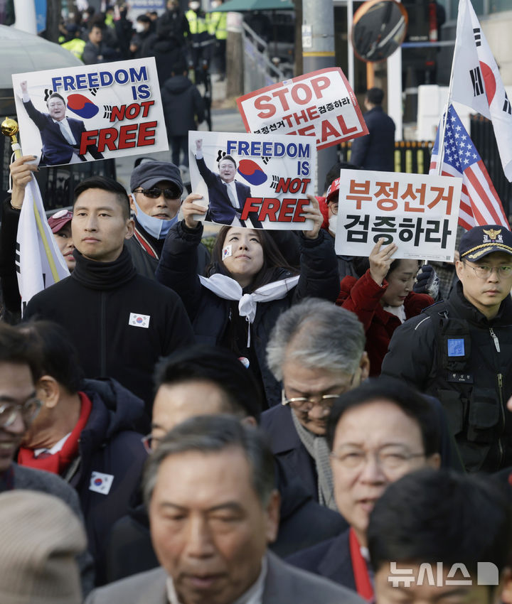 [서울=뉴시스] 최동준 기자 = 법원이 윤석열 대통령의 구속취소 청구를 인용한 7일 서울 용산구 한남동 대통령 관저 앞에서 국민의힘 탄핵반대 당협위원장 모임 관계자들이 윤 대통령 석방을 환영 입장문을 발표하는 뒤로 지지자들이 손팻말을 흔들고 있다. 2025.03.07. photocdj@newsis.com