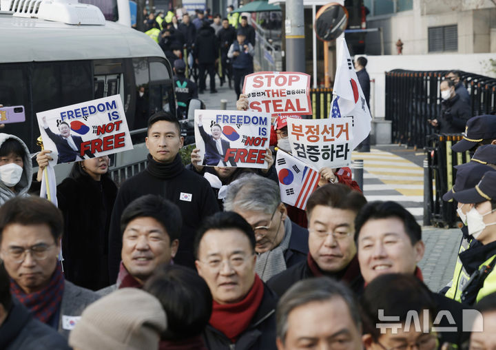 [서울=뉴시스] 최동준 기자 = 법원이 윤석열 대통령의 구속취소 청구를 인용한 7일 서울 용산구 한남동 대통령 관저 앞에서 국민의힘 탄핵반대 당협위원장 모임 관계자들이 윤 대통령 석방을 환영 입장문을 발표하는 뒤로 지지자들이 손팻말을 흔들고 있다. 2025.03.07. photocdj@newsis.com