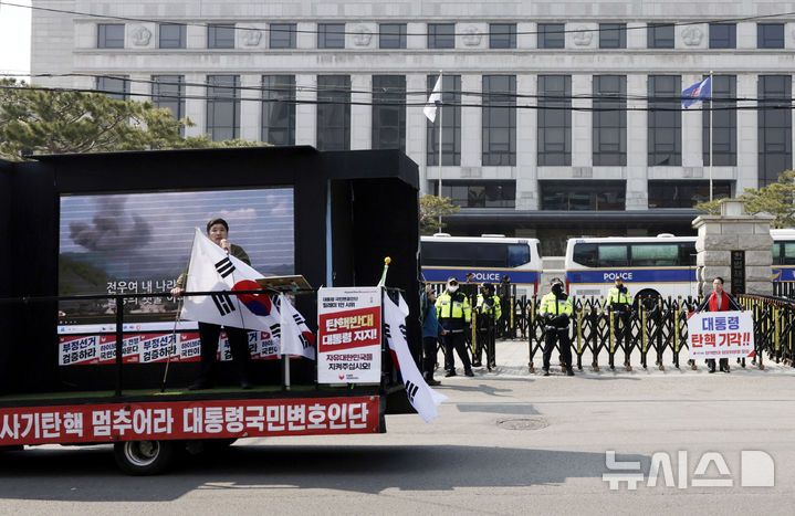 [서울=뉴시스] 최동준 기자 = 9일 서울 종로구 헌법재판소 앞에서 경찰 병력이 경계 근무를 서고 있는 가운데 국민의힘 탄핵반대 당협위원장 모임, 대통령국민변호인단이 탄핵 기각을 촉구하고 있다. 2025.03.09. photocdj@newsis.com