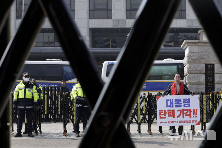 [서울=뉴시스] 최동준 기자 = 9일 서울 종로구 헌법재판소 앞에서 경찰 병력이 경계 근무를 서고 있는 가운데 국민의힘 탄핵반대 당협위원장 모임이 윤석열 대통령 탄핵 기각 촉구 1인 시위를 하고 있다. 2025.03.09. photocdj@newsis.com