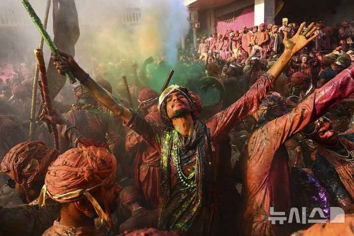 [난드가온=AP/뉴시스] 9일(현지 시간) 인도 뉴델리 남쪽 115㎞ 떨어진 난드가온 마을의 난드그람 사원에서 라트마르 홀리 축제가 열려 색가루 투성이의 주민들이 춤추며 노래하고 있다. 2025.03.10.