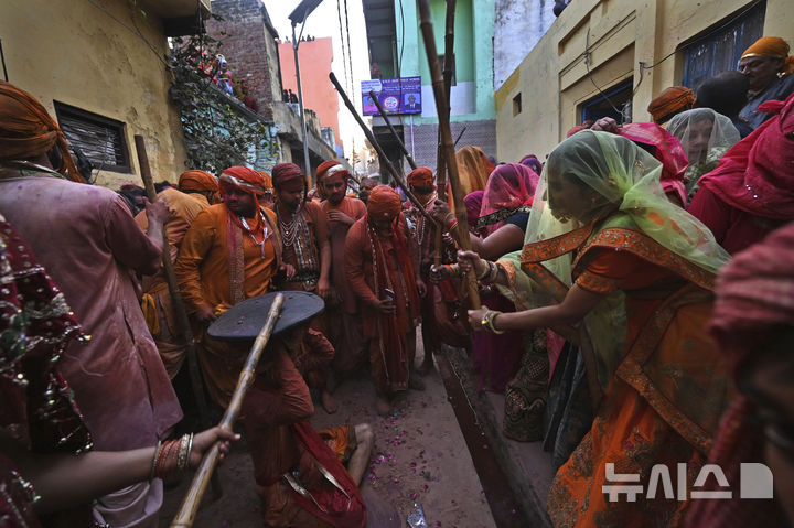[난드가온=AP/뉴시스] 9일(현지 시간) 인도 뉴델리 남쪽 115㎞ 떨어진 난드가온 마을의 난드그람 사원에서 라트마르 홀리 축제가 열려 여성들이 막대기를 휘두르고 있다. 2025.03.10.