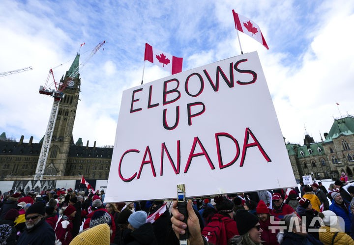 [오타와=AP/뉴시스] 9일(현지 시간) 캐나다 오타와 의회 언덕에서 도널드 트럼프 미국 대통령의 캐나다 주권에 대한 발언 규탄 집회가 열려 한 참가자가 '엘보스 업 캐나다'(Elbows Up Canada)라고 쓰인 팻말을 들고 있다. '엘보스 업'은 아이스하키에서 상대를 밀쳐내는 동작으로, 캐나다의 강한 대응을 상징한다. 한편, 트럼프 대통령은 캐나다를 '미국의 51번째 주'라고 조롱한 바 있다. 2025.03.10.