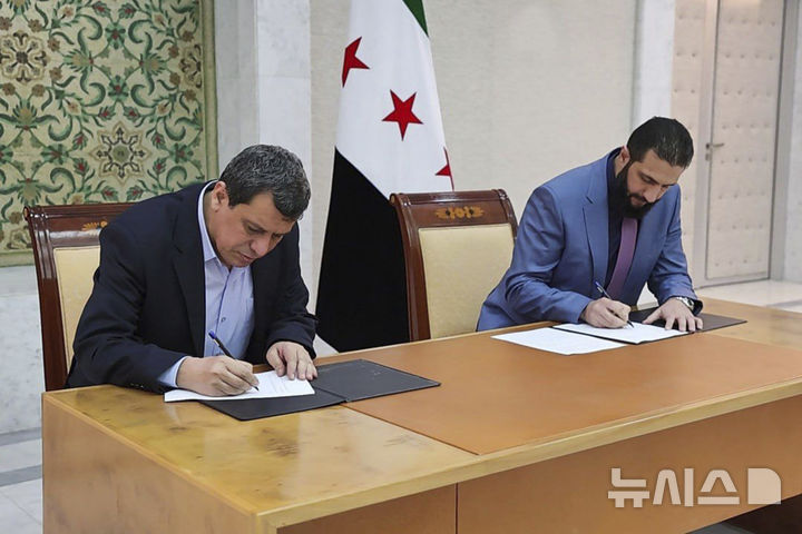 [다마스쿠스=AP/뉴시스]아마드 알샤라 시리아 임시 대통령(오른쪽)과  마즐룸 압디 시리아민주군(SDF) 사령관이 10일(현지시각) 두 세력의 통합 합의서에 서명하고 있다. 2025.3.11. 