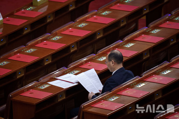 [베이징=AP/뉴시스] 중국 최대 연례 정치행사 양회(전국인민대표대회와 전국인민정치협상회의)가 폐막한 가운데 민간경제 지원을 강화하는 법안이 이번 양회에서 통과되지 않았다. 사진은 11일 전국인민정치협상회의(전인대) 폐막식을 앞두고 한 전인대 대표가 투표 서류를 살펴보는 모습. 2025.03.12