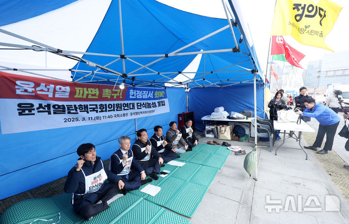 [서울=뉴시스] 홍효식 기자 = 윤석열탄핵국회의원연대 소속 의원들이 11일 오후 서울 종로구 경복궁 서십자각 인근 농성장에서 윤석열 대통령 파면 촉구 및 헌정수호를 위한 단식농성에 돌입하며 구호를 외치고 있다.왼쪽부터 사회민주당 한창민, 더불어민주당 민형배, 박수현, 진보당 윤종오, 더불어민주당 김준혁, 강득구 의원. 2025.03.11. yesphoto@newsis.com