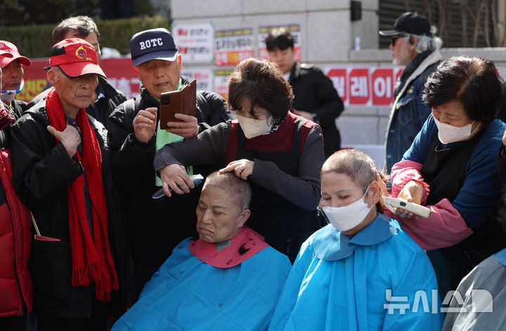 [서울=뉴시스] 김선웅 기자 = 헌재의 윤석열 대통령에 대한 탄핵심판 선고가 임박한 13일 서울 종로구 헌법재판소 앞에서 친 윤 성향 시민들이 탄핵을 반대하며 삭발을 하고 있다. 2025.03.13. mangusta@newsis.com