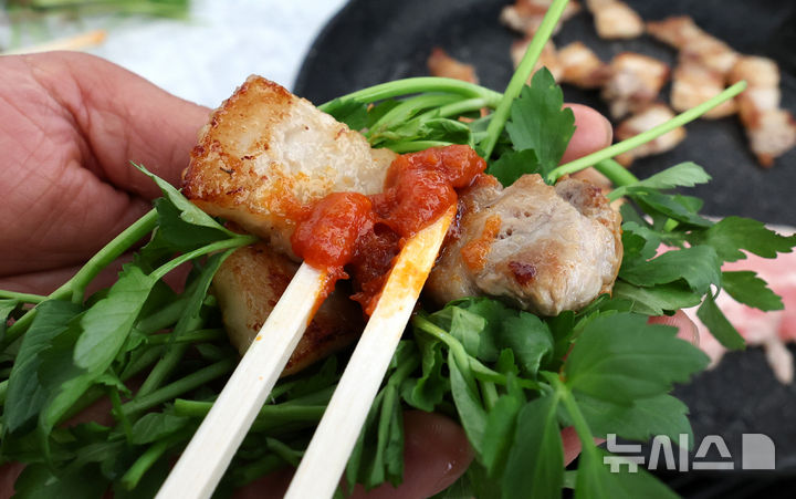 [대구=뉴시스] 이무열 기자 = 지난 3월 14일 대구에서 열린 미나리·삼겹살 소비촉진 행사에서 시민들이 구매한 미나리와 삼겹살을 즉석에서 구워 맛보고 있다. 해당 사진은 기사와 직접 관련이 없습니다. 2025.03.14. lmy@newsis.com