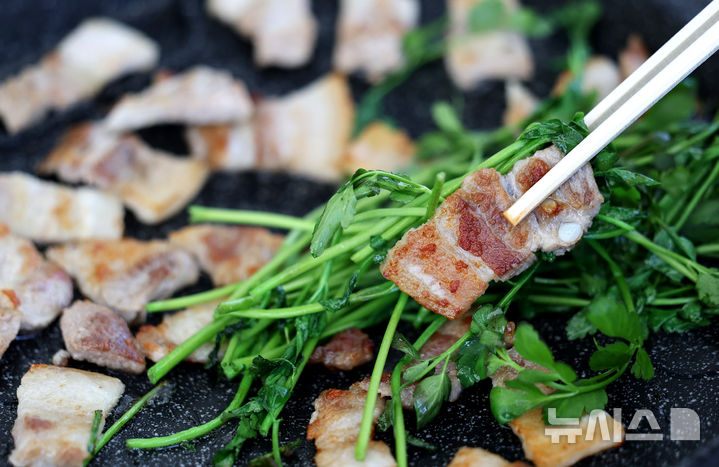 [대구=뉴시스] 이무열 기자 = 14일 대구 달서구 옛 두류정수장에서 열린 미나리·삼겹살 소비촉진 행사에서 시민들이 구매한 미나리와 삼겹살을 즉석에서 구워 맛보고 있다. 2025.03.14. lmy@newsis.com