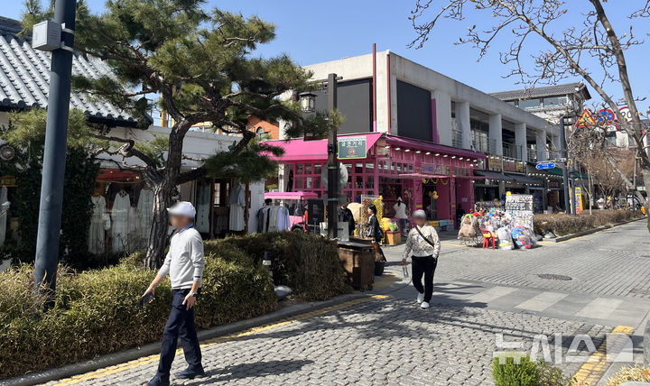 [전주=뉴시스] 강경호 기자 = 14일 전북 전주시 완산구 전주 한옥마을 일대의 거리를 걷는 관광객들 뒤로 한옥마을의 이미지와 맞지 않는 이질적인 분홍색 콘크리트 건물의 오락 시설이 들어서 있다. 2025.03.14. lukekang@newsis.com