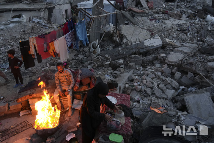 [자발리아=AP/뉴시스] 17일(현지 시간) 가자지구 자발리아에서 피란민들이 파괴된 가옥 앞에서 음식을 조리하고 있다. 2025.03.18.