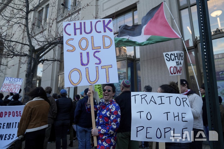 [볼티모어=AP/뉴시스] 17일(현지 시간) 미국 메릴랜드주 볼티모어에 있는 에녹 프랫 공공 도서관 앞에서 민주당 지지자들이 척 슈머 상원 민주당 원내대표를 비판하는 시위를 벌이고 있다. 슈머 원내대표는 이곳에서 신간 행사를 개최할 예정이었지만 안전상의 문제로 취소했다. 2025.03.18.