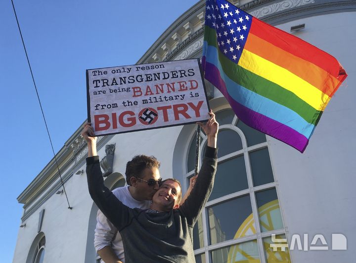 [샌프란시스코=AP/뉴시스] 사진은 2017년 7월26일 미국 샌프란시스코에서 열린 집회에서 한 커플이 트랜스젠더 군복무 금지안에 반대하며 무지개 깃발을 흔들고 있는 모습.