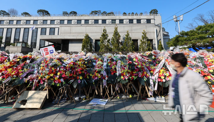 [서울=뉴시스] 이영환 기자 = 윤석열 대통령 탄핵심판 선고가 예상보다 늦어지고 있는 19일 오전 서울 종로구 헌법재판소 앞에 윤 대통령 지지자들이 보낸 화환이 놓여 있다.  헌법재판소 사무처장이 지난 달 26일까지 자진 정비를 요청하며 적치물 정비 예고통지서를 부착했지만 화환은 방치되고 있다. 2025.03.19. 20hwan@newsis.com