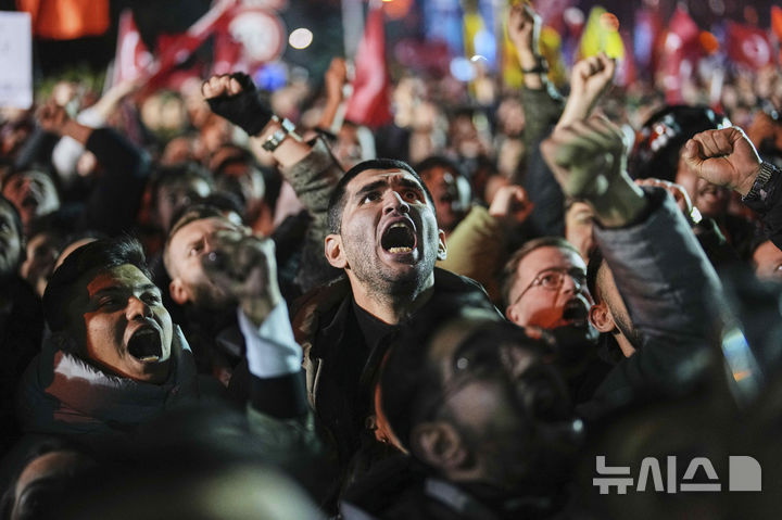 [이스탄불=AP/뉴시스] 19일(현지 시간) 튀르키예 이스탄불 시청 앞에서 시민들이 에크렘 이마모을루 시장 체포에 항의하며 구호를 외치고 있다. 튀르키예 검찰은 레제프 타이이프 에르도안 대통령의 유력 대권 경쟁자인 이마모을루 이스탄불 시장을 부패와 테러 연루 혐의로 체포했다. 2025.03.20.