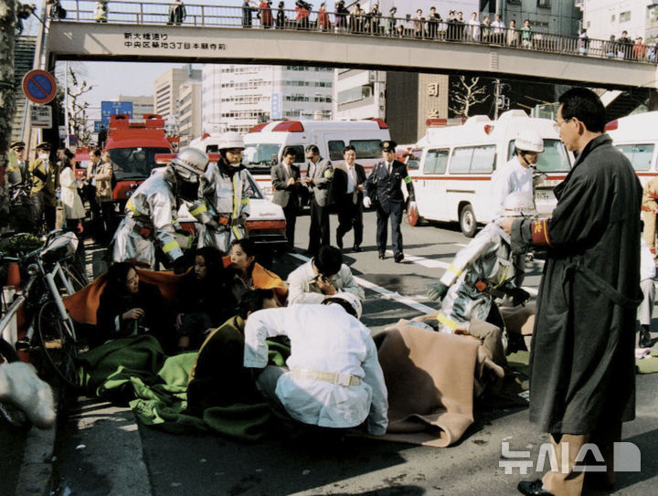 [도쿄=AP·교도/뉴시스]1995년 3월 20일 도쿄의 한 지하철역 인근에서 옴진리교 사린 테러로 부상한 시민들이 치료를 받고 있다. 2025.03.20.