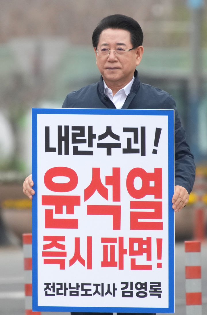 [무안=뉴시스] 송창헌 기자 = 김영록 전남지사가 27일 오전 무안군 삼향읍 농협 사거리 앞에서 출근길 차량과 시민들을 향해 윤석열 대통령 탄핵을 촉구하는 1인 시위를 하고 있다. (사진=독자 제공) 2025.03.27 photo@newsis.com *재판매 및 DB 금지
