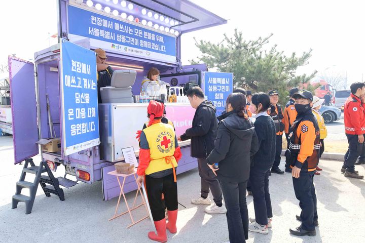 [서울=뉴시스] 현지 주민들과 소방대원들이 간식차 앞에서 간식을 받기 위해 기다리는 모습. 2025.03.27 (사진 제공=성동구청) photo@newsis.com *재판매 및 DB 금지