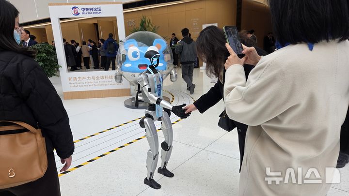 [베이징=뉴시스] 박정규 특파원 = 중국의 첨단기술 포럼인 '2025년 중관춘 포럼 연례회의가 27∼31일 '신품질 생산력과 글로벌 과학기술 협력'을 주제로 개최된다. 28일 오전 포럼 행사장 로비에서 관람객이 휴머노이드 로봇과 악수하고 있다. 2025.03.28 pjk76@newsis.com