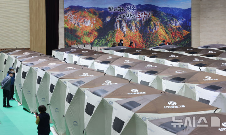 [청송=뉴시스] 김금보 기자 = 경북 청송군 청송국민체육센터에 마련된 산불 대피소 이재민 텐트 뒤로 산불피해를 입기전 주왕산 사진이 보이고 있다. 2025.03.28. kgb@newsis.com