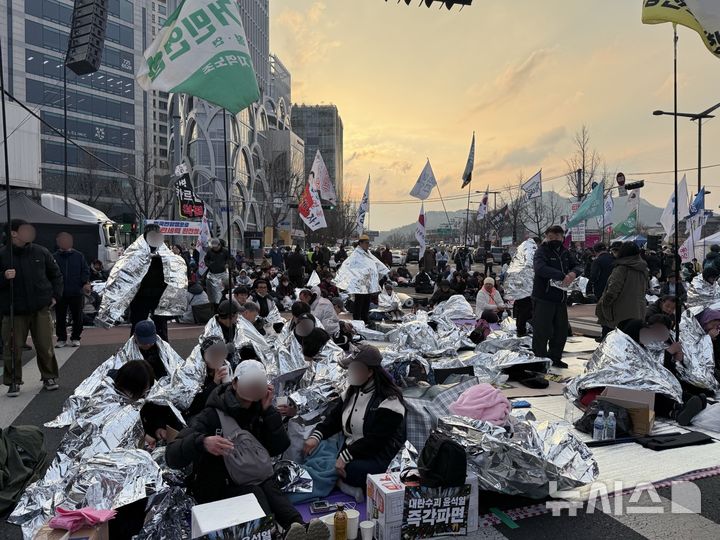 [서울=뉴시스] 이수정 기자=헌법재판소 인근 안국역 6번 출구 앞에서 윤 대통령 파면을 촉구하는 탄핵 찬성 측 집회 참가자들이 은박지를 두른 채 앉아있다. 2025.04.02. crystal@newsis.com
