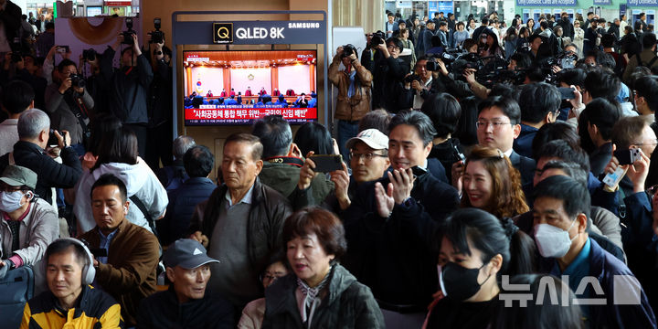 [서울=뉴시스] 박주성 기자 = 4일 오전 서울 용산구 서울역 역사에서 시민들이 윤석열 대통령 탄핵심판 선고를 시청하고 있다. 2025.04.04. park7691@newsis.com